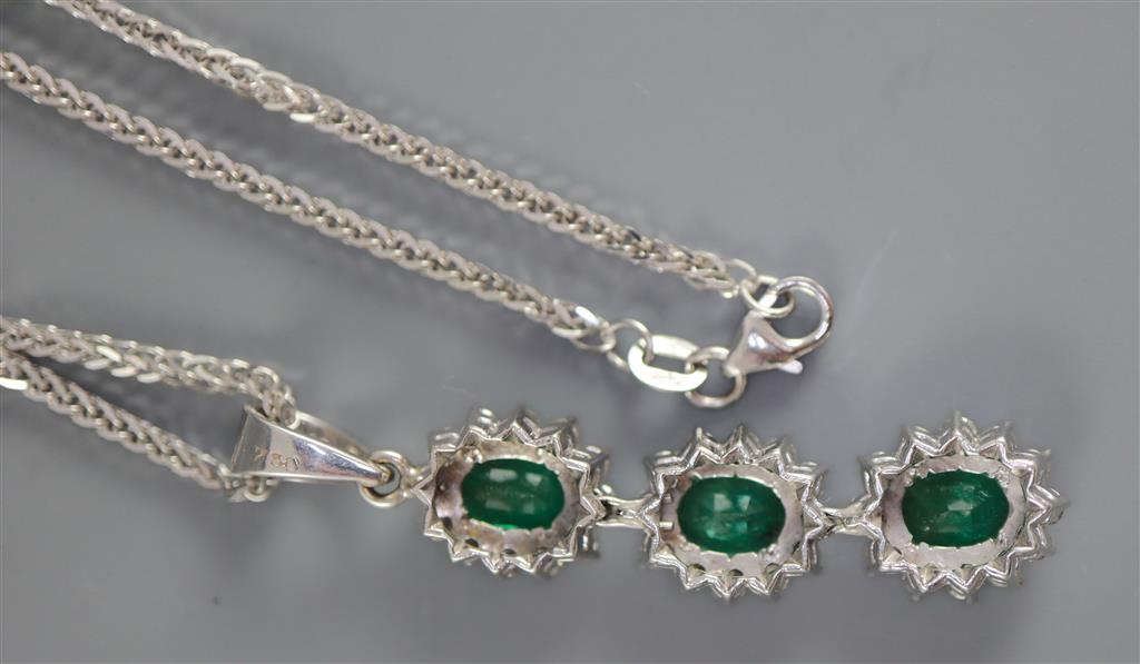 A modern 18ct white gold, emerald and diamond set oval triple cluster drop pendant, on an 18ct white gold chain,